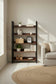 Librero Bergen 120 cm Nogal en rincón de sala con sofá beige y tapete de yute, decorado con canasta, plantas, jarrones y libros, diseño industrial-minimalista atemporal