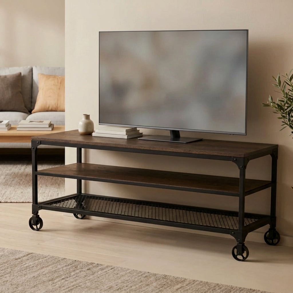 Mesa para TV industrial modelo Nashville en acabado de madera color nogal con estructura de metal negro, repisa de rejilla y ruedas, con televisión sobre la cubierta en una sala con sofá.